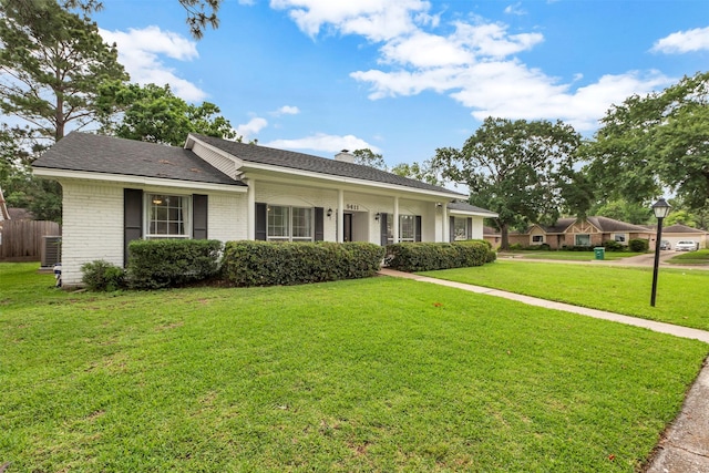 single story home featuring a chimney, central AC unit, brick siding, fence, and a front lawn