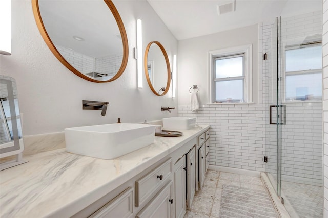 bathroom featuring visible vents, a sink, double vanity, and a shower stall