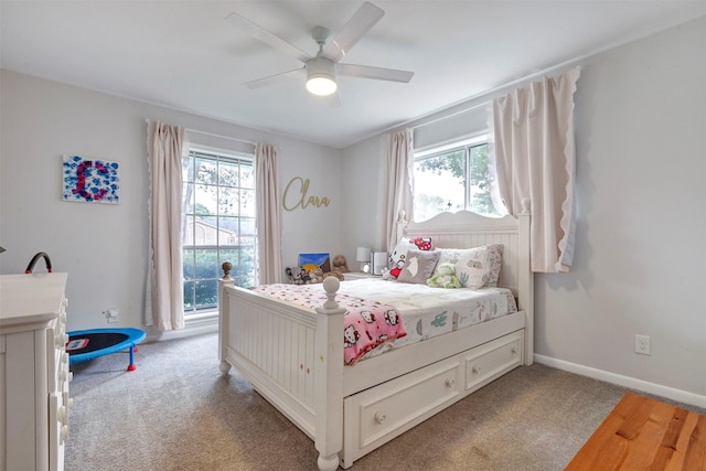 bedroom with ceiling fan, multiple windows, baseboards, and light carpet