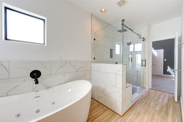 full bathroom featuring visible vents, a freestanding tub, wood finished floors, tile walls, and a stall shower