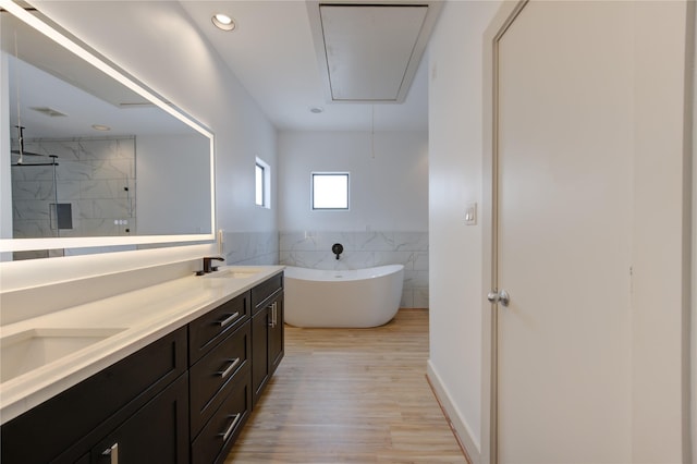 full bathroom with a sink, double vanity, a marble finish shower, a freestanding tub, and tile walls