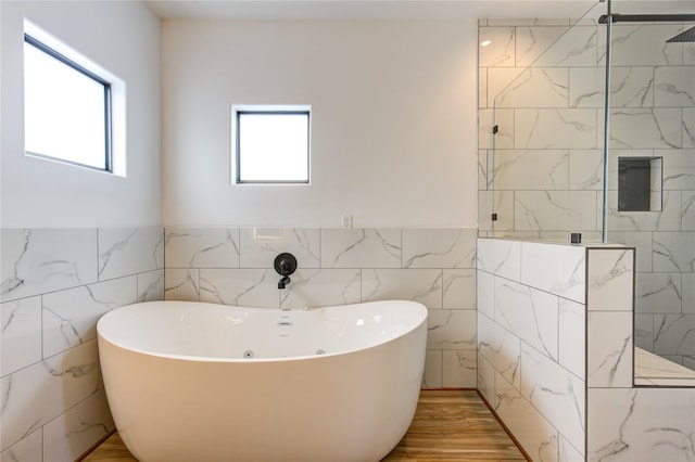 bathroom featuring a freestanding tub, tile walls, and plenty of natural light
