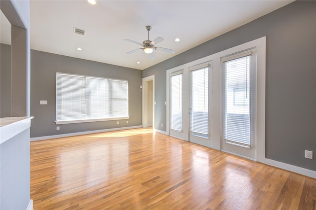 unfurnished room with light wood-style floors, baseboards, a ceiling fan, and visible vents