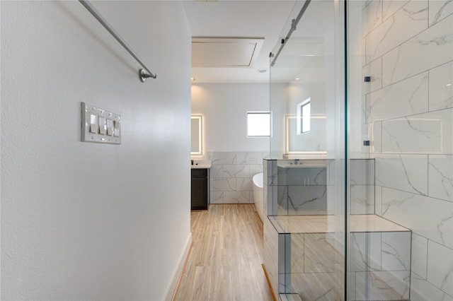 bathroom featuring vanity, tile walls, a marble finish shower, and wood finished floors