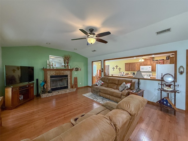 5325 County Road 2691, Buffalo, TX 75831 - living room featuring visible vents, a brick fireplace, light wood-style flooring, and ceiling fan