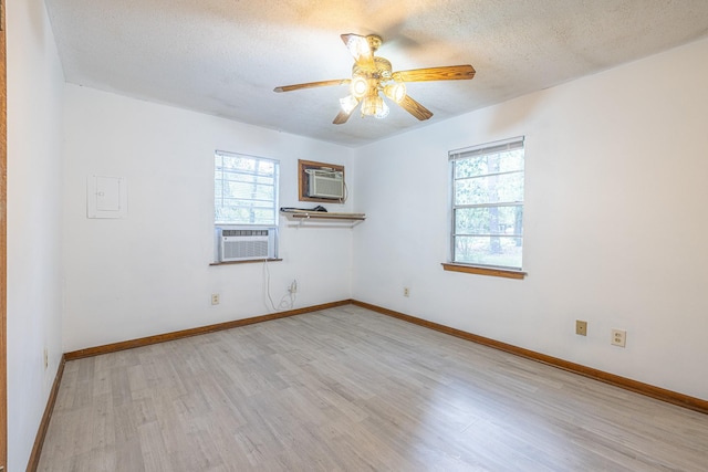9847 N Lake Vw, Montgomery, TX 77316 - empty room featuring plenty of natural light, light wood-style flooring, a wall mounted AC, ceiling fan, and a textured ceiling