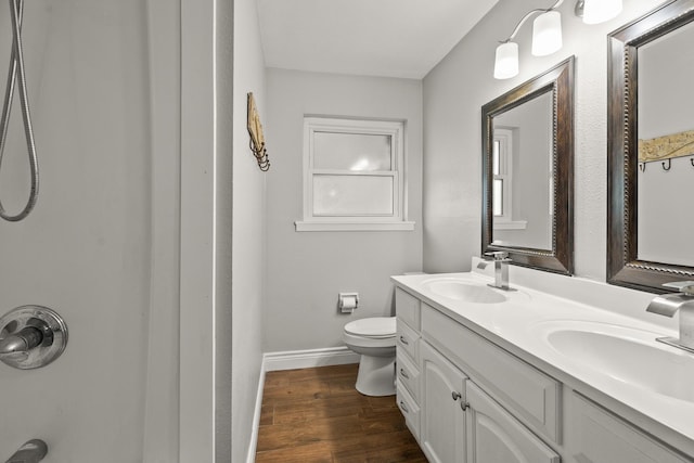 bathroom with a sink, double vanity, toilet, and wood finished floors