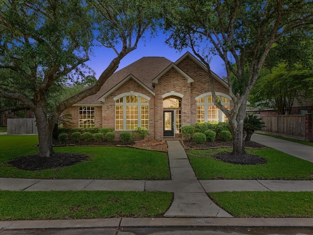 view of front of house featuring fence, a front lawn, and brick siding