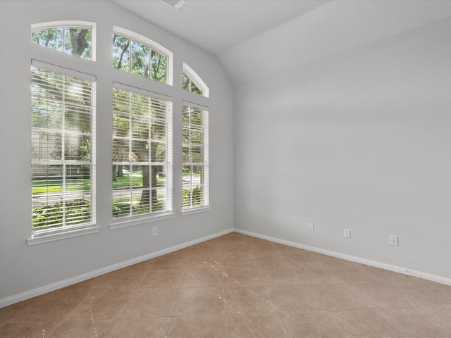 empty room featuring light tile patterned floors, a healthy amount of sunlight, and vaulted ceiling