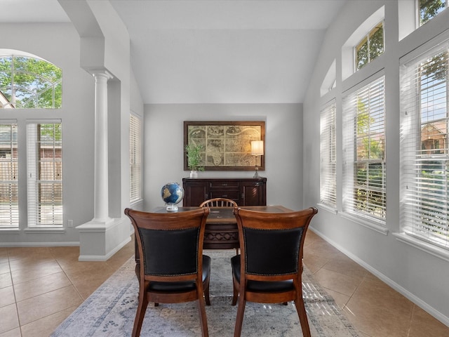 tiled dining space featuring baseboards, decorative columns, and lofted ceiling