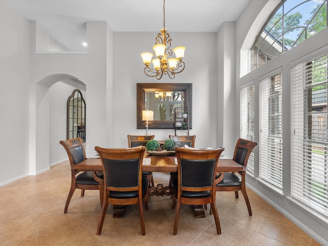 dining area with arched walkways, a towering ceiling, light tile patterned floors, and a notable chandelier