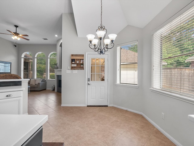 interior space featuring a fireplace, ceiling fan with notable chandelier, light tile patterned flooring, and a wealth of natural light