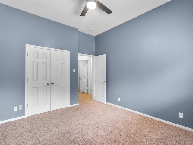 unfurnished bedroom featuring a high ceiling, carpet, a ceiling fan, baseboards, and a closet