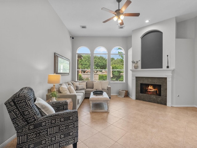 living room with visible vents, baseboards, a tiled fireplace, a ceiling fan, and light tile patterned floors