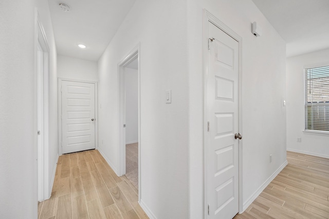 corridor featuring baseboards, recessed lighting, and light wood-style flooring