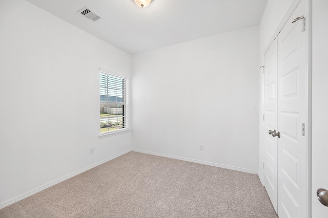 empty room featuring baseboards, light carpet, and visible vents