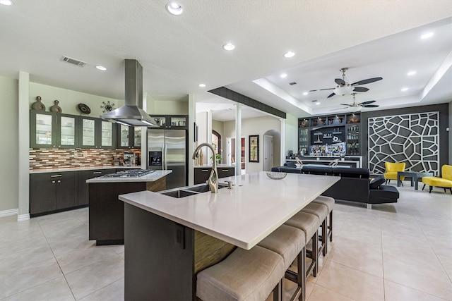 33519 Hillside Dr, Pinehurst, TX 77362 - kitchen with a kitchen island with sink, a sink, island range hood, stainless steel appliances, and ceiling fan