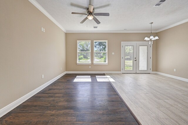 unfurnished living room featuring crown molding, ceiling fan with notable chandelier, wood finished floors, and visible vents