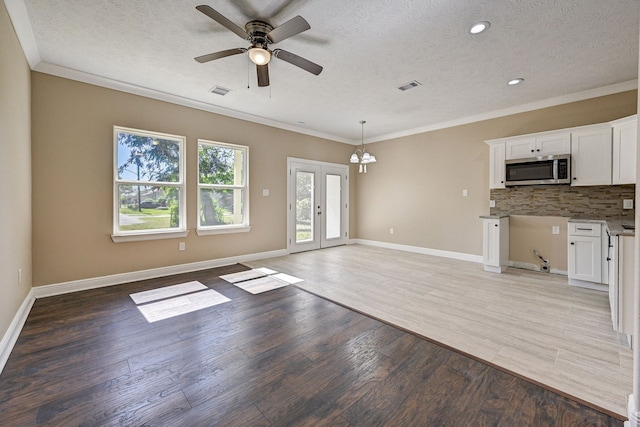 unfurnished living room with a textured ceiling, visible vents, and light wood-style floors