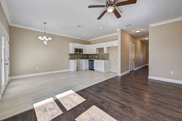 unfurnished living room with crown molding, light wood-style floors, ceiling fan with notable chandelier, baseboards, and visible vents