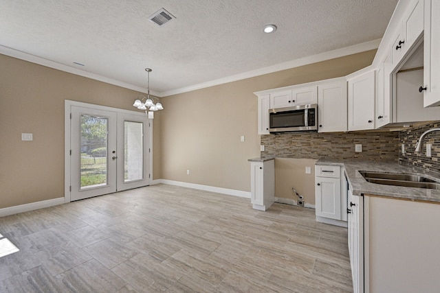 kitchen featuring stainless steel microwave, visible vents, a sink, and tasteful backsplash