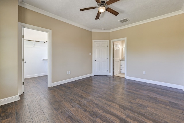empty room featuring ornamental molding, a ceiling fan, baseboards, visible vents, and dark wood-style floors