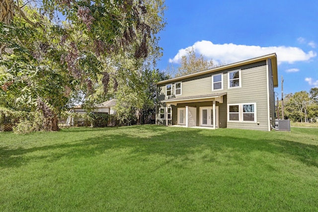 rear view of property with a lawn and central AC