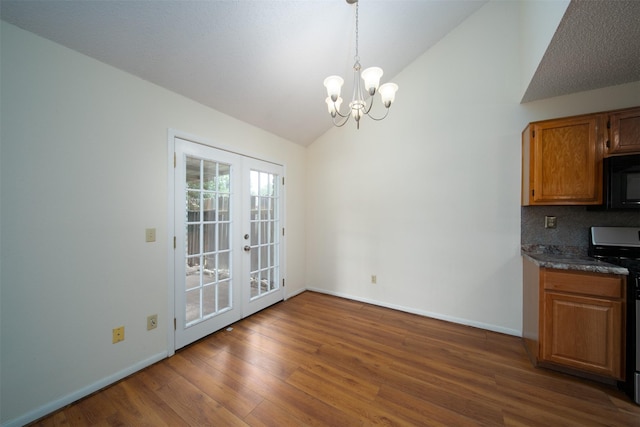 unfurnished dining area featuring french doors, baseboards, wood finished floors, and an inviting chandelier
