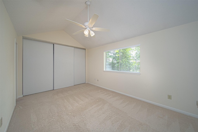unfurnished bedroom featuring a closet, lofted ceiling, and light carpet