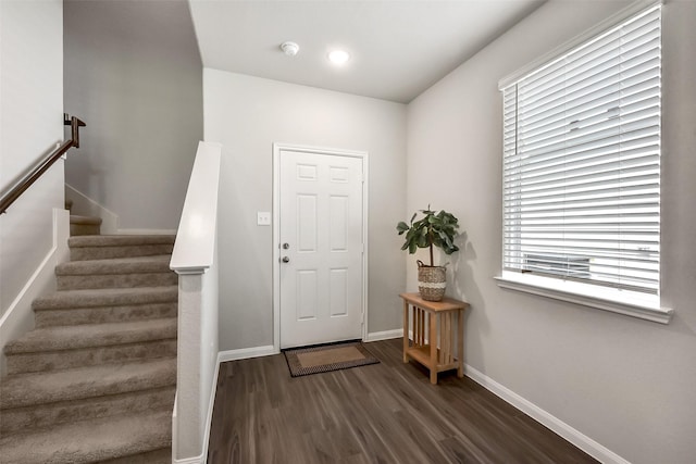 foyer entrance featuring dark wood-type flooring, baseboards, and a wealth of natural light