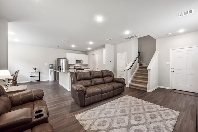 living room with visible vents, baseboards, and dark wood finished floors
