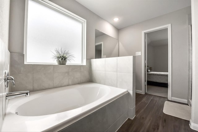 bathroom with recessed lighting, baseboards, wood finished floors, and a bath
