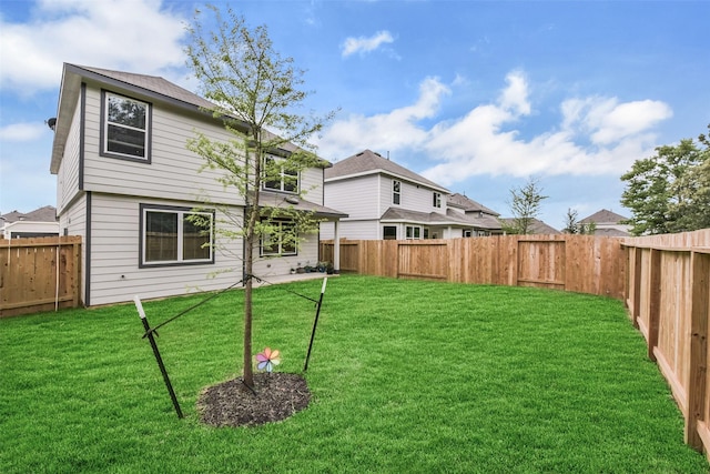 back of property with a lawn and a fenced backyard
