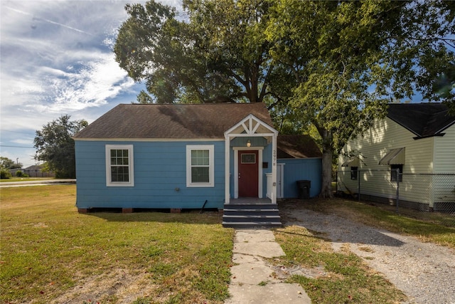 bungalow with a shingled roof and a front yard