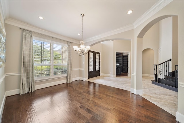 unfurnished dining area featuring stairs, arched walkways, ornamental molding, and wood finished floors