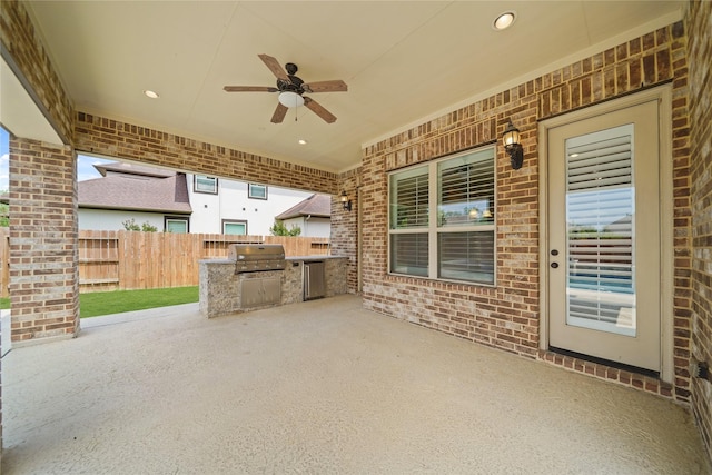 view of patio featuring a ceiling fan, fence, area for grilling, and an outdoor kitchen