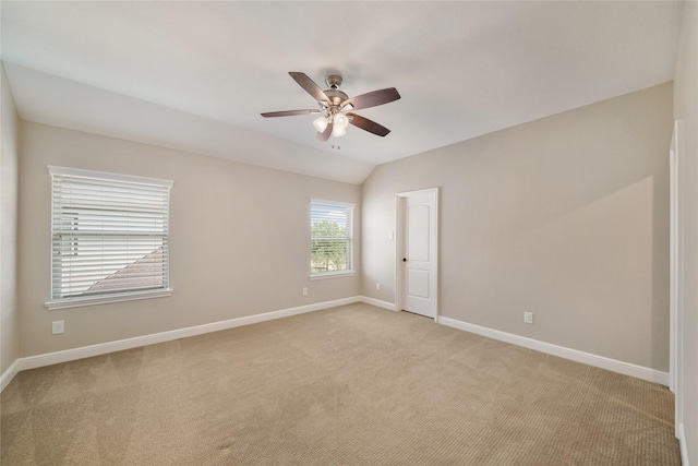 unfurnished room with baseboards, a ceiling fan, vaulted ceiling, and light carpet