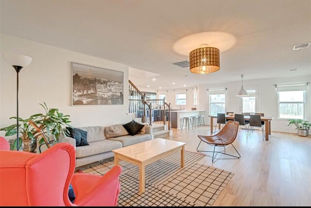 living room featuring stairway, plenty of natural light, wood finished floors, and visible vents