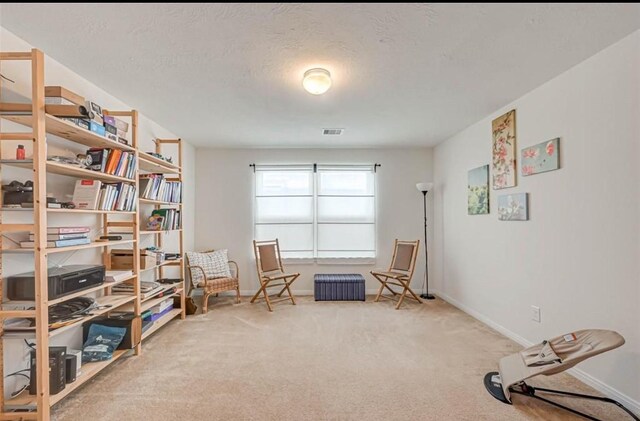 living area featuring visible vents, carpet, and baseboards