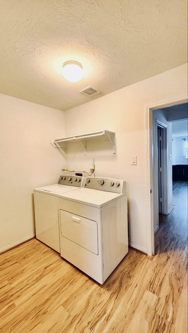 clothes washing area featuring baseboards, light wood-style flooring, independent washer and dryer, and visible vents