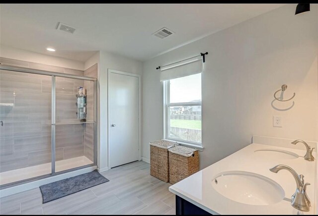 full bath with a sink, a shower stall, double vanity, and visible vents