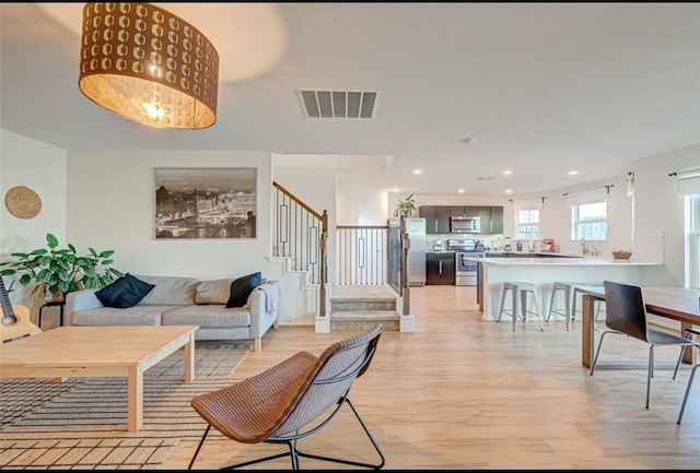 living room featuring visible vents, recessed lighting, stairway, and light wood-type flooring
