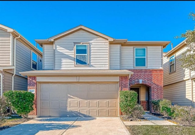 traditional home with brick siding, an attached garage, and driveway