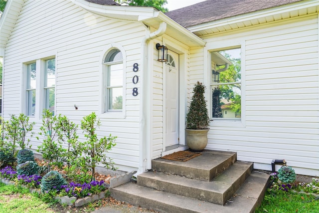 entrance to property featuring a shingled roof