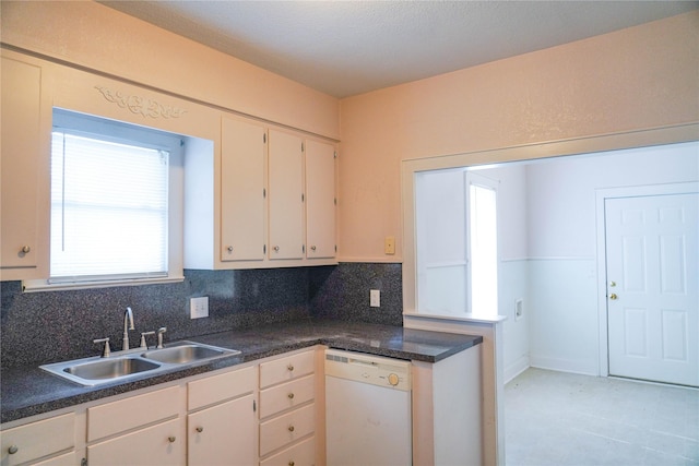 kitchen with a sink, dishwasher, dark countertops, and tasteful backsplash
