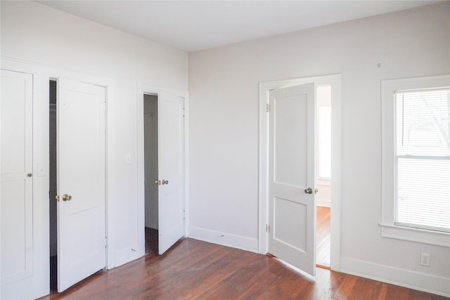 unfurnished bedroom featuring baseboards and dark wood-type flooring