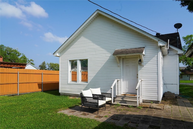 back of property featuring fence, a lawn, and a patio area