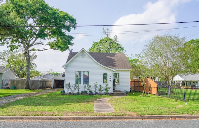 bungalow featuring dirt driveway, a front lawn, fence, and a shingled roof