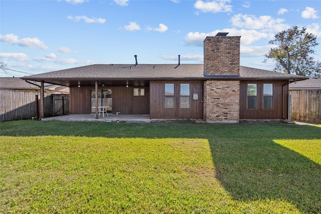 back of house featuring a lawn, a patio, a chimney, and a fenced backyard