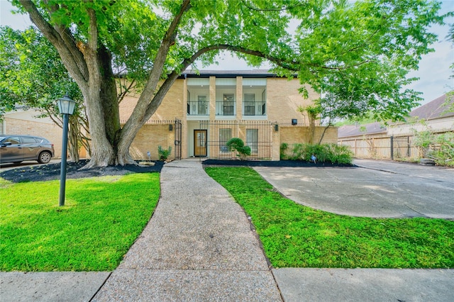 view of front of house with fence, a front lawn, and brick siding